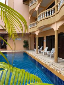 uma piscina num hotel com cadeiras e um edifício em Baan Sudarat Hotel em Praia de Patong