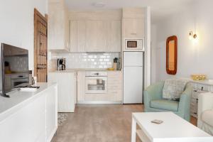 una cocina con armarios blancos y una silla azul en Capistrano Village, 1 bedroom, en Nerja