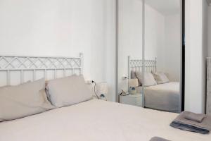 Habitación blanca con cama y espejo en Capistrano Village, 1 bedroom, en Nerja
