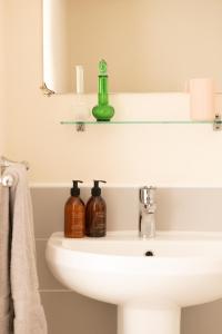 un lavabo con espejo y una botella verde. en Charming 2BD Cottage wIth beautiful views nr Bath en Batheaston