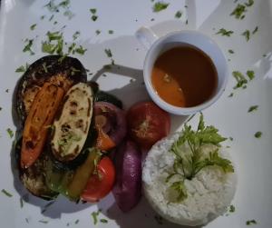 un piatto di cibo con riso e una ciotola di zuppa di Mount Zion Lodge a Michamvi Kae