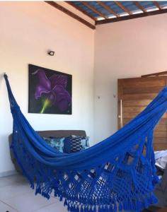 uma rede azul num quarto com uma flor roxa em Mykonos Residence em São Miguel do Gostoso