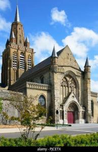 uma velha igreja com uma torre e uma porta vermelha em Maison chez fredo em Calais