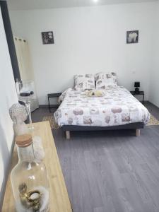 Un dormitorio con una cama y una mesa con una botella de cristal en Maison chez fredo, en Calais