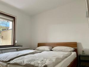 a bedroom with a bed with white sheets and a window at Ruhige Innenstadtlage mit Terrasse und Netflix in Kassel