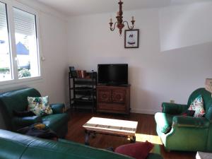 sala de estar con 2 sofás verdes y TV en Etoile, en Questembert