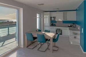 uma cozinha com uma mesa de madeira e cadeiras azuis em 5 Sterne Penthouse DeichSuite em Büsum