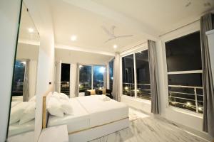 um quarto com uma cama branca e janelas grandes em RK MOUNT ORCHID coorg em Madikeri