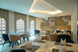 a dining room with tables and chairs and windows at C - Hotel and Suites Doha in Doha