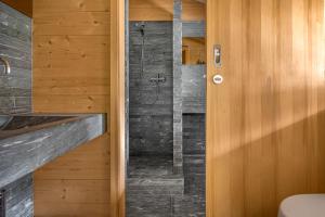 a bathroom with a walk in shower next to a wooden door at Rupicapra in Bettmeralp +35 photos