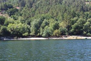 um corpo de água com árvores e uma praia em Casa de Casarelhos - Casa de férias - Gerês em Gerês