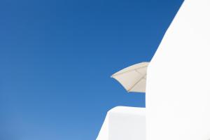 an open white umbrella against a blue sky at Ploes Seaside Houses in Plaka