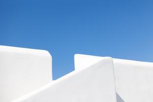 a white building with a blue sky in the background at Ploes Seaside Houses in Plaka