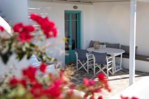a patio with a table and chairs and red flowers at Ploes Seaside Houses in Plaka