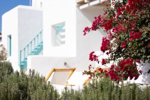 a white building with red flowers in front of it at Ploes Seaside Houses in Plaka