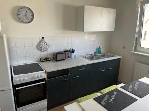a kitchen with a stove and a sink and a clock at Zentrale Lage - 2 Einzelbetten - Waschmaschine - Badewanne - WLAN - Netflix - 5min zum Bahnhof in Zwickau +7 photos