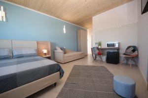 1 dormitorio con 1 cama, 1 silla y 1 sofá en Ohana Holiday Rooms, en Rosolina Mare