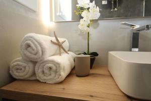 a bathroom with towels on a wooden counter next to a sink at Ohana Holiday Rooms in Rosolina Mare
