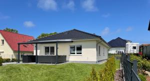 a white house with a black roof at Ferienhaus Meerzeit in Bastorf