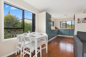 a kitchen and dining room with a white table and chairs at Pipi Cabin - Mangawhai Village Bach in Mangawhai