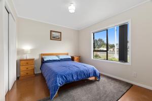 a bedroom with a bed and a window at Pipi Cabin - Mangawhai Village Bach in Mangawhai