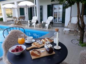 een tafel met ontbijtproducten naast een zwembad bij Casinha da Colina in Alfândega da Fé