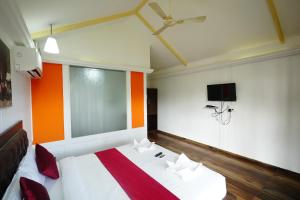 a bedroom with a bed and a tv on the wall at Sunset & Waves Resort in Mandrem