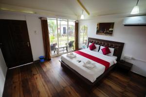 a bedroom with a large bed with red pillows at Sunset & Waves Resort in Mandrem