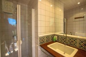 y baño de azulejos blancos con lavabo y ducha. en Kerzen - villa avec accès à la plage de Morgat, en Crozon