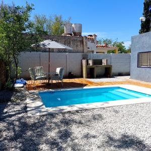 einen Pool im Garten mit Tisch und Stühlen in der Unterkunft Jazmin del Cielo in Capilla del Monte