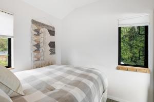 a white bedroom with a bed and two windows at River Otter in Nehalem