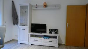 Zimmer mit einem weißen Entertainment-Center und einem Flachbild-TV in der Unterkunft Ferienwohnungen Walter in Cuxhaven