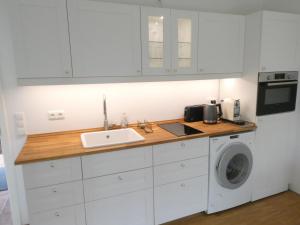 a kitchen with white cabinets and a sink and a washing machine at Ländliches HideAway zwischen Hamburg und Lübeck in Köthel