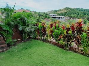KārleにあるAashraay Bungalowの椰子の木と柵のある庭園