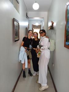 Tres mujeres de pie en un pasillo posando para una foto en 100 RV Apartments Iquitos-Apartamento primer piso con vista a piscina en Iquitos