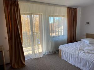 - une chambre avec un lit et une grande fenêtre dans l'établissement Pensiunea Joe Paltinis, à Păltiniş
