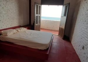 1 dormitorio con cama y ventana grande en CASA DE PRAIA (PE NA AREIA), en Caponga