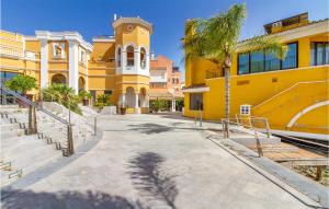 a yellow building with a palm tree in front of it at Gorgeous Home In Torre-pacheco With Swimming Pool in Torre-Pacheco