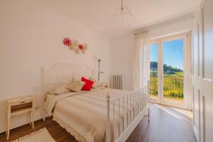 Dormitorio blanco con cama y ventana grande en Casa Rafanelli, en Monforte dʼAlba