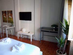 Il comprend un salon doté d'un lit blanc et d'une télévision. dans l'établissement Oporto Batalha Nice View Flat, à Porto