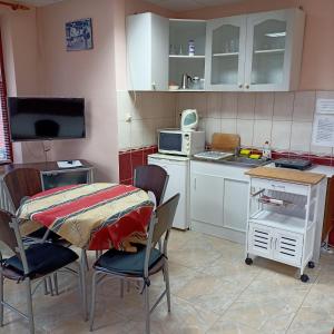 een keuken met een tafel en stoelen en een magnetron bij Lívia Apartman in Bük