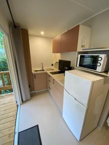 La cuisine est équipée d'un réfrigérateur blanc et d'un four micro-ondes. dans l'établissement Camping 3 étoiles Les Fougères, à Rivedoux-Plage