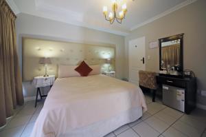 a bedroom with a large white bed and a desk at Savoy Lodge in Cape Town