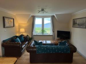 a living room with two leather couches and a window at Taigh Mara(Marine House) 2 bed Apartment in Fort William
