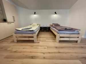 Modern guest house in city center I Room 1 في فيلنيوس: سريرين في غرفة ذات أرضيات خشبية