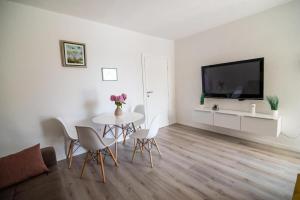 ein weißes Wohnzimmer mit einem Tisch und einem TV in der Unterkunft Villa Tia Čitluk in Čitluk