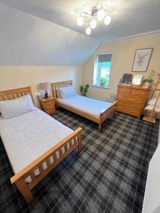 a bedroom with two beds and a dresser at Taigh Mara(Marine House) 2 bed Apartment in Fort William