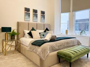 a bedroom with a large bed with a green ottoman at Large Blythswood Residence in Glasgow