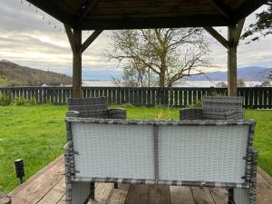 a group of chairs sitting on a bench under a gazebo at Taigh Mara(Marine House) 2 bed Apartment in Fort William