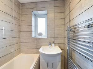 a bathroom with a sink and a tub and a mirror at Stunning Family Home with Comfortable Surroundings in Wigan